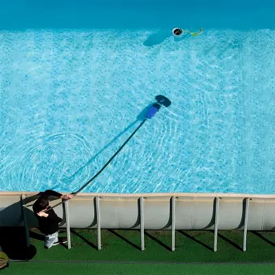 Nettoyage du fond d'une piscine hors-sol avec un balai aspirateur