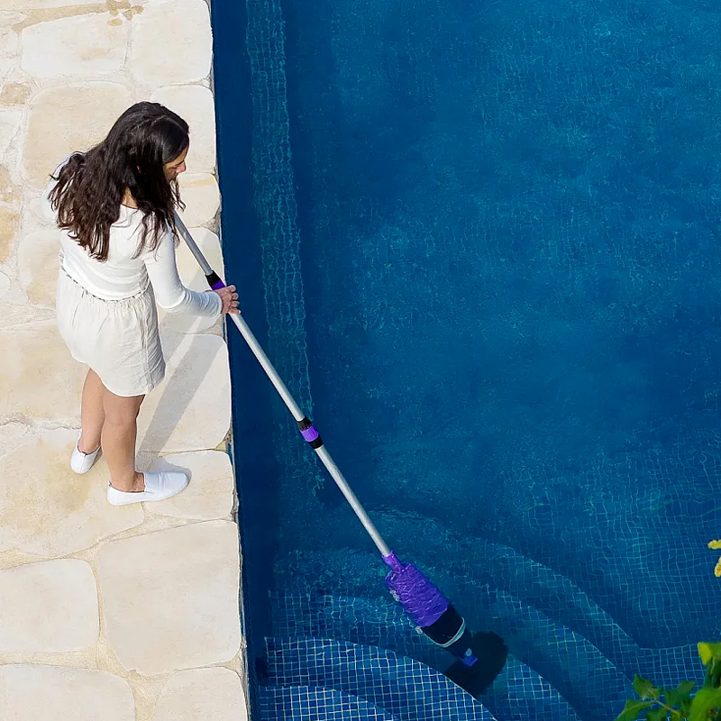 Nettoyage manuel des marches d'une piscine avec un balai aspirateur